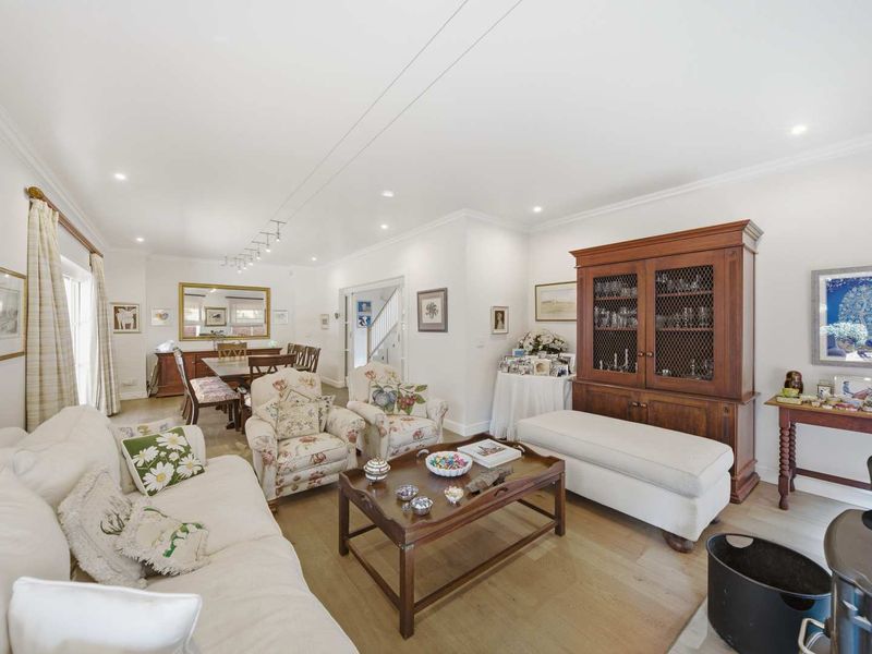 Spacious open-plan living and dining area featuring light timber flooring, recessed downlighting, and elegant crown molding, creating a bright and inviting atmosphere.