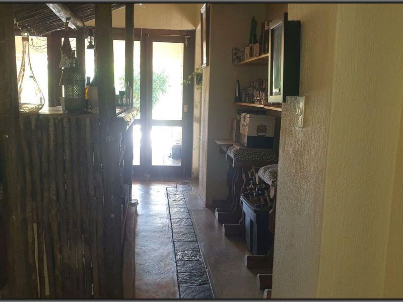 Rustic indoor bar area featuring a built-in timber counter, stone tile flooring, and direct access to an outdoor patio through glass panelled doors.