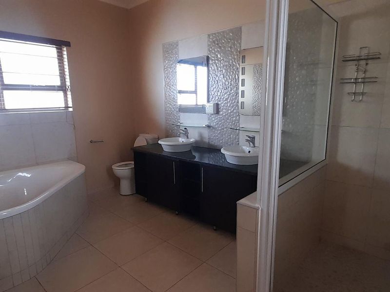 Spacious bathroom featuring a corner bathtub, double vanity with modern basins, and a separate glass-enclosed shower with tiled finishes.
