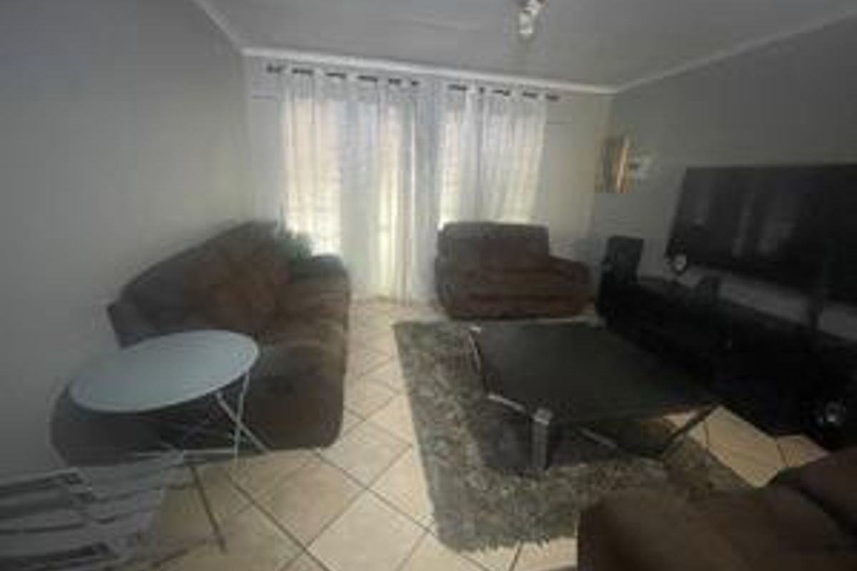 A living room featuring tiled flooring and a sliding glass door providing natural light.