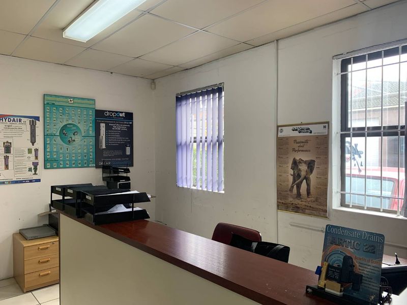 A functional office space featuring a built-in reception counter, security bars on windows, and a suspended ceiling with integrated lighting.