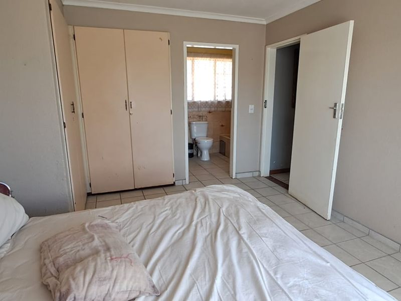 Bedroom featuring tiled flooring, built-in cupboards, and direct access to an en-suite bathroom.