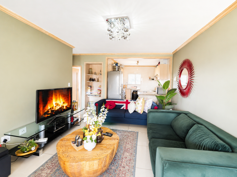 Open-plan living area featuring tiled floors, crown molding, and a connected kitchen space with built-in cabinetry and shelving.