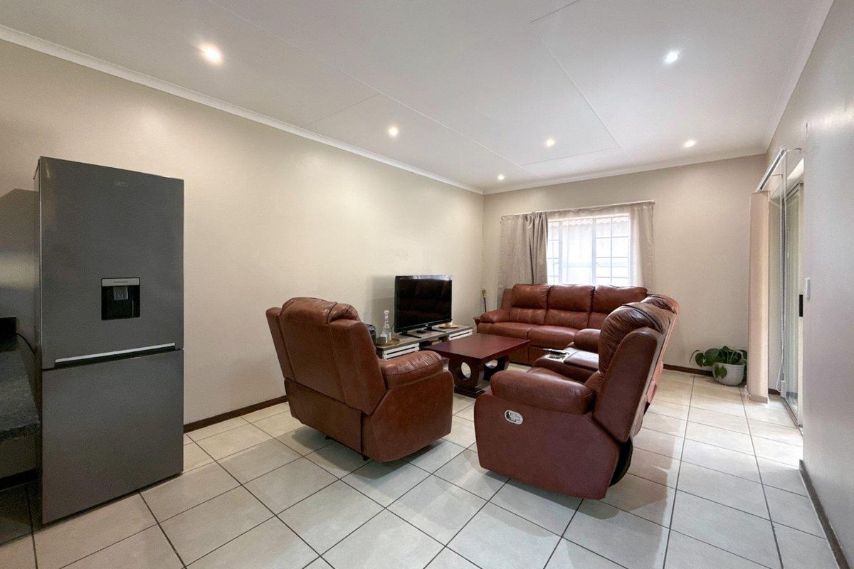A spacious living area featuring neutral tiled flooring, recessed ceiling lighting, and large sliding glass doors providing access to the exterior.