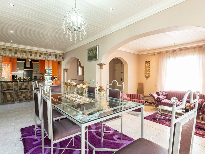 Spacious open-plan living and dining area featuring a stone-clad breakfast bar, arched architectural details, and a bright, neutral aesthetic.