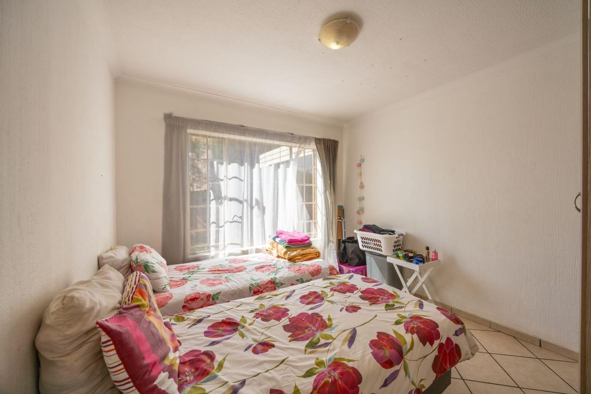 A bedroom featuring tiled flooring, a central ceiling light, and a window with curtain tracks, providing a functional space for rest.