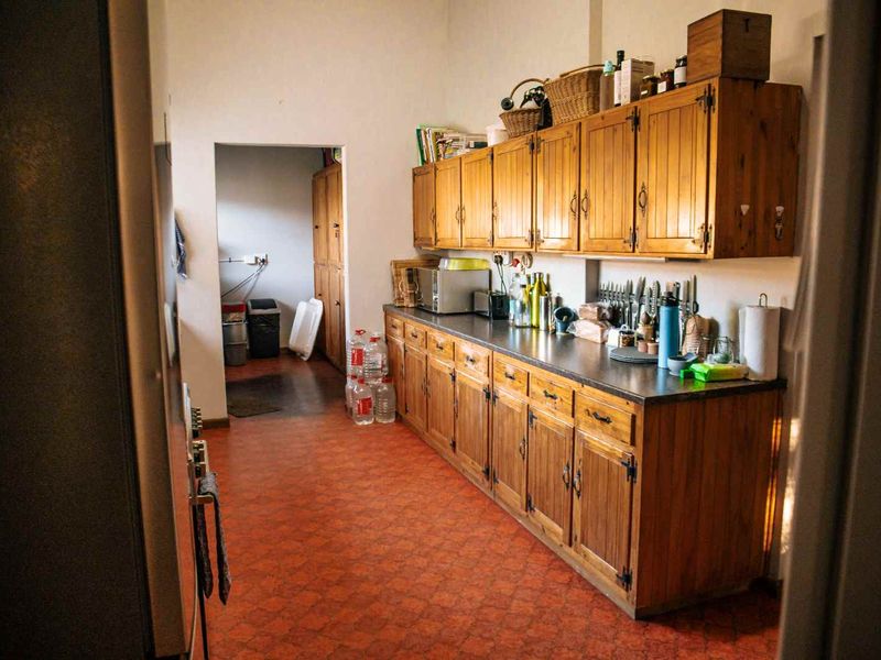 A functional kitchen featuring traditional wooden cabinetry, ample storage space, and durable vinyl flooring, offering potential for a modern renovation.