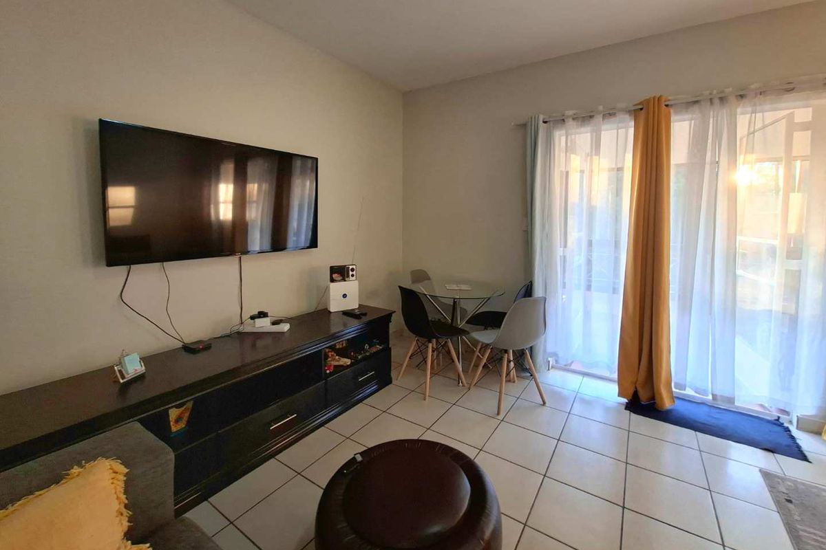 A living room featuring tiled flooring and a sliding glass door providing access to the outdoor area.