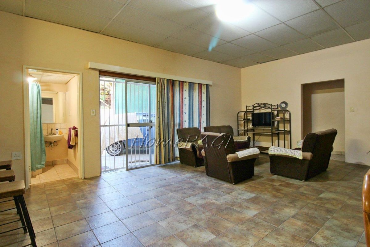 Spacious living area featuring tiled flooring, a drop ceiling, and sliding glass doors providing direct access to the exterior.