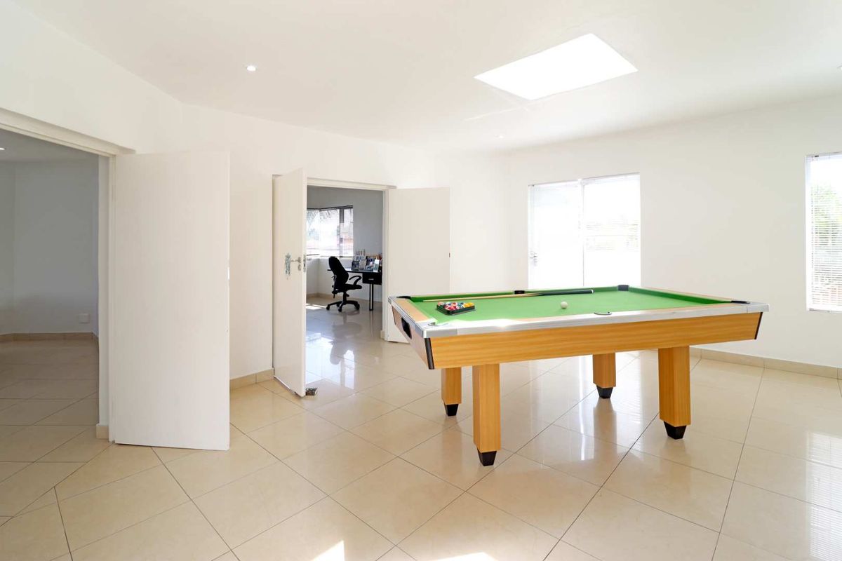 Spacious living area featuring neutral floor tiles, a skylight, and double door access to an adjacent room.