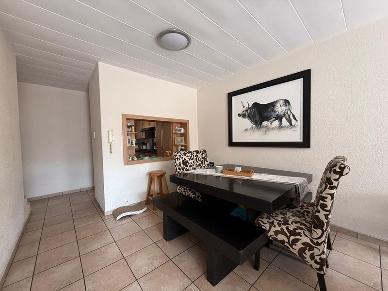 Dining area featuring tiled flooring and a convenient serving hatch connecting to the kitchen space.