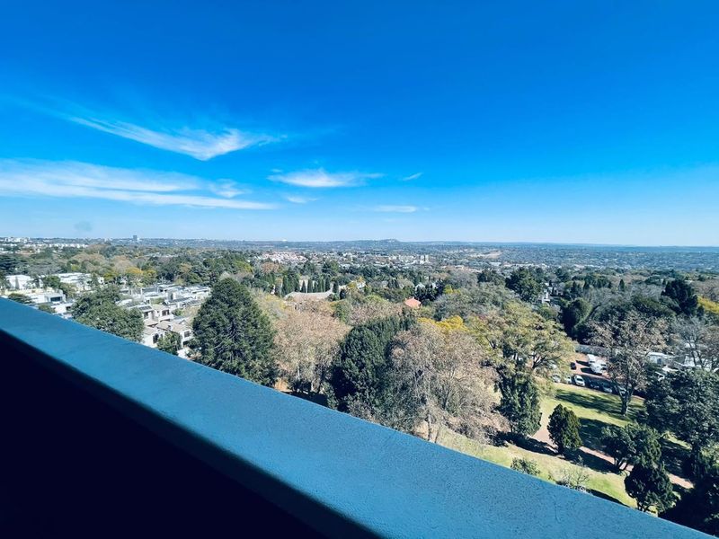 An elevated panoramic view of the surrounding neighborhood and lush green landscape, captured from a balcony.