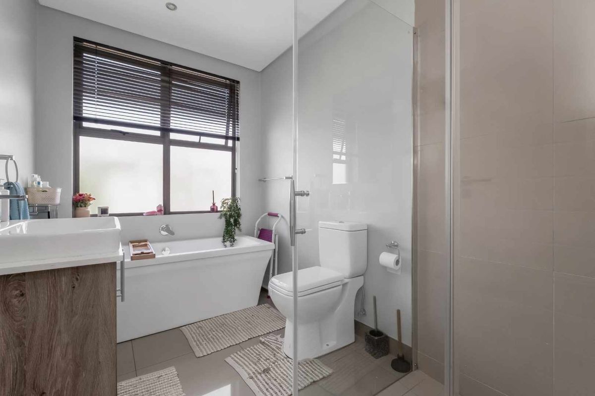 Modern bathroom featuring a freestanding bathtub, glass-enclosed shower, vanity with basin, and neutral tiling, offering a clean and functional space.