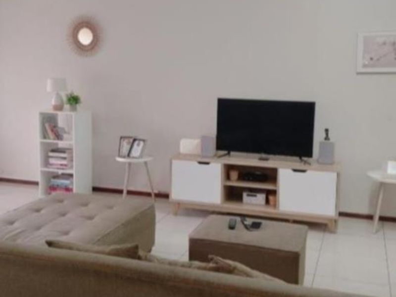 A living room area featuring neutral tiled flooring and a simple, open layout suitable for various furniture arrangements.