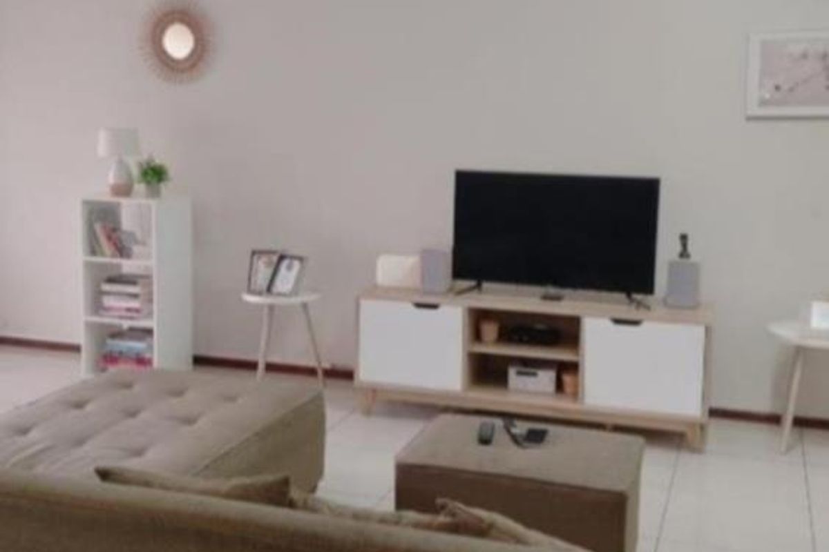 A living room area featuring neutral tiled flooring and a simple, open layout suitable for various furniture arrangements.