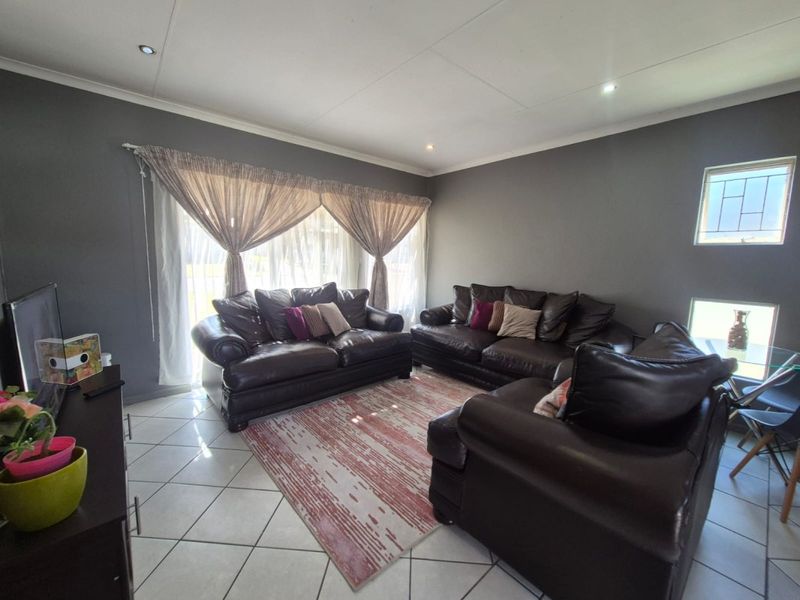 A spacious living room featuring tiled flooring, recessed downlighting, and a large sliding glass door providing natural light.