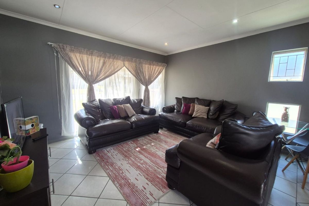 A spacious living room featuring tiled flooring, recessed downlighting, and a large sliding glass door providing natural light.