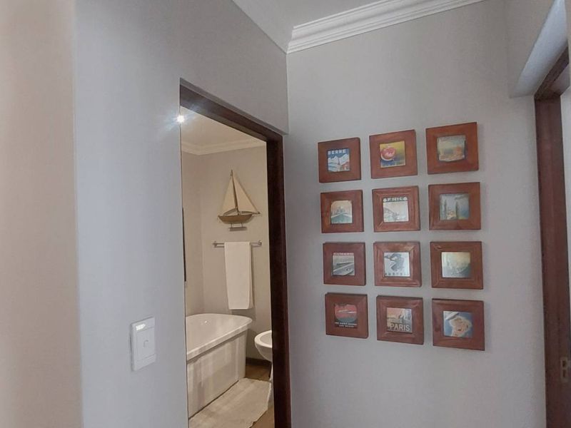 A view through a hallway leading into a bathroom, featuring crown molding and neutral wall finishes.