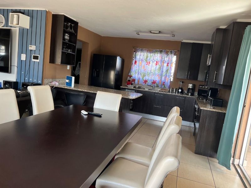 Open plan kitchen and dining area featuring dark cabinetry, granite countertops, and tiled flooring, creating a functional space for cooking and entertaining.