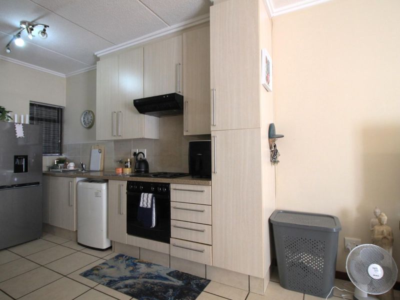 A functional kitchen featuring light-toned built-in cabinetry, laminate countertops, a built-in oven with hob, extractor fan, and tiled flooring.