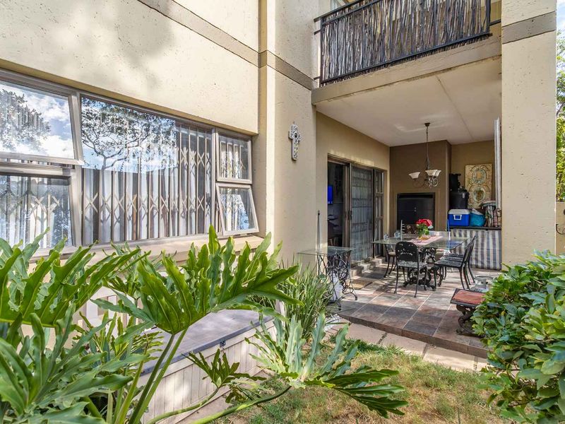 Covered patio area featuring a built-in braai, tiled flooring, and direct access to the garden through sliding doors.