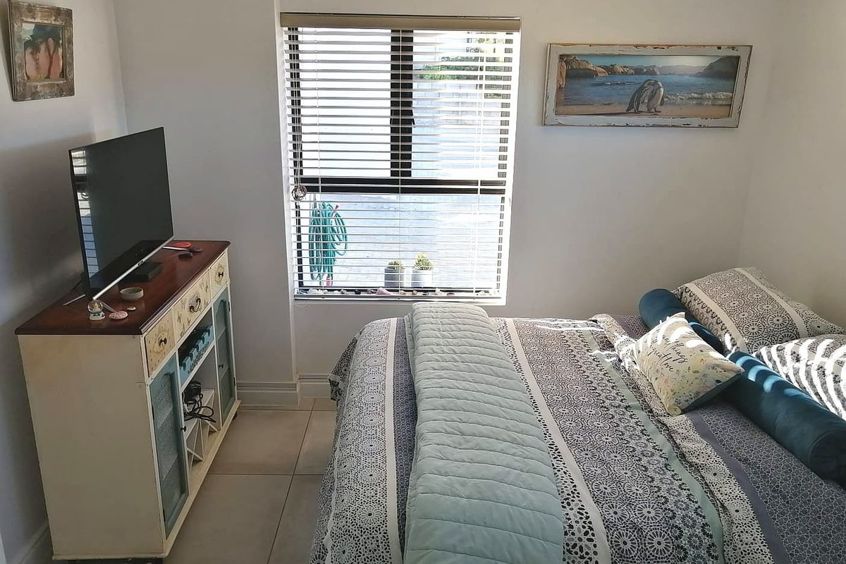 A compact bedroom featuring tiled flooring and a window fitted with horizontal blinds, providing natural light to the space.