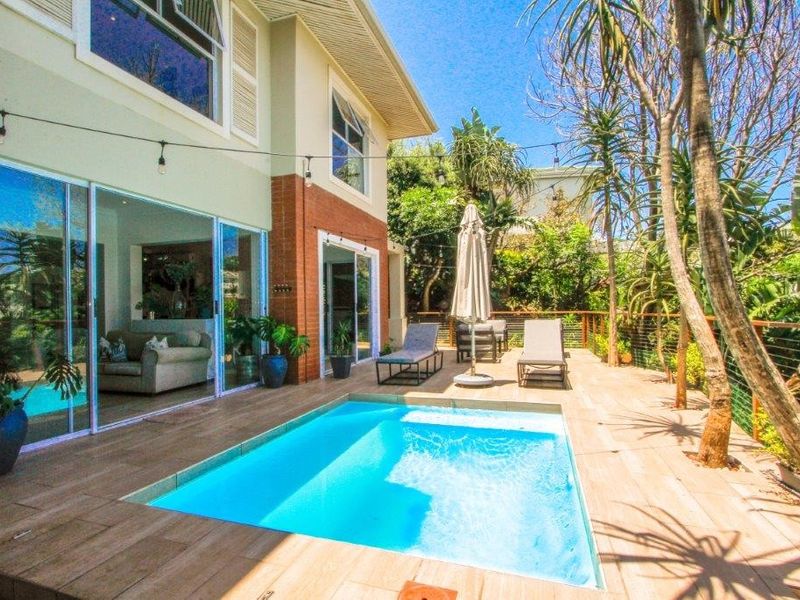 A well-maintained outdoor pool area featuring timber decking, a swimming pool, and direct access to the interior living space through large sliding glass doors.