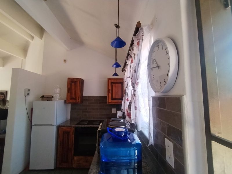 A functional kitchen featuring built-in wooden cabinetry, granite countertops, a built-in oven, and a tiled backsplash with pendant lighting.