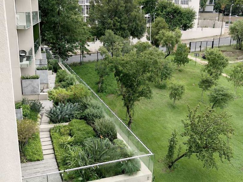 Elevated view overlooking a well-maintained landscaped garden area with timber decking and modern glass balustrades.