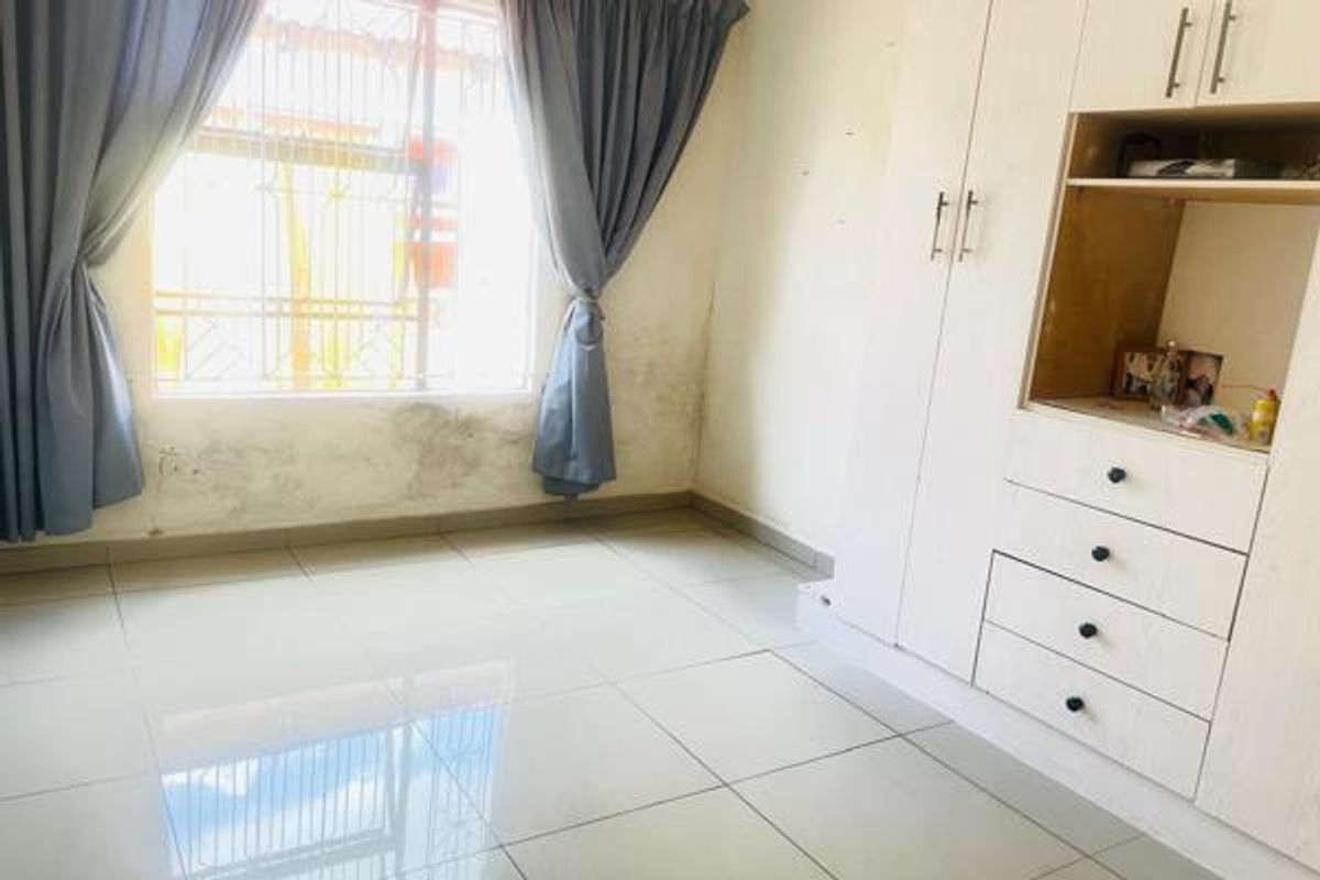 A bedroom featuring tiled flooring and built-in cabinetry, with visible signs of wall dampness requiring maintenance.