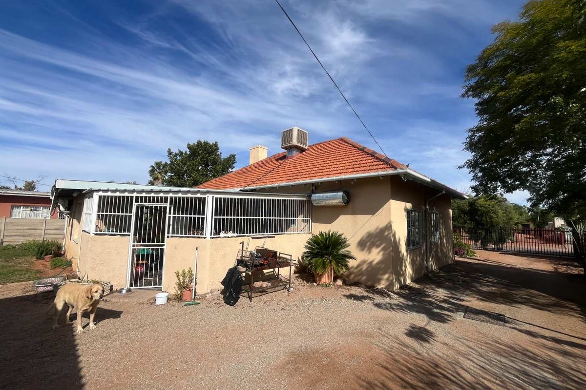 Rear view of the house featuring a tiled roof, evaporative cooling unit, and a covered patio area with security bars.