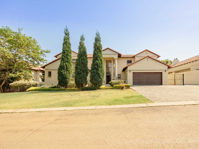 A well-maintained double-story residential property featuring a paved driveway, double garage, and an attractive landscaped front garden with mature trees.
