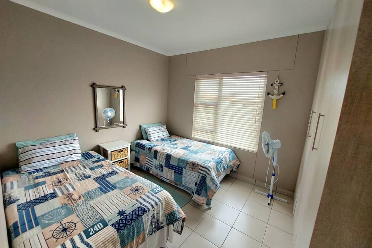 A functional bedroom featuring tiled flooring, built-in cupboards, and horizontal window blinds, providing a practical and comfortable living space.