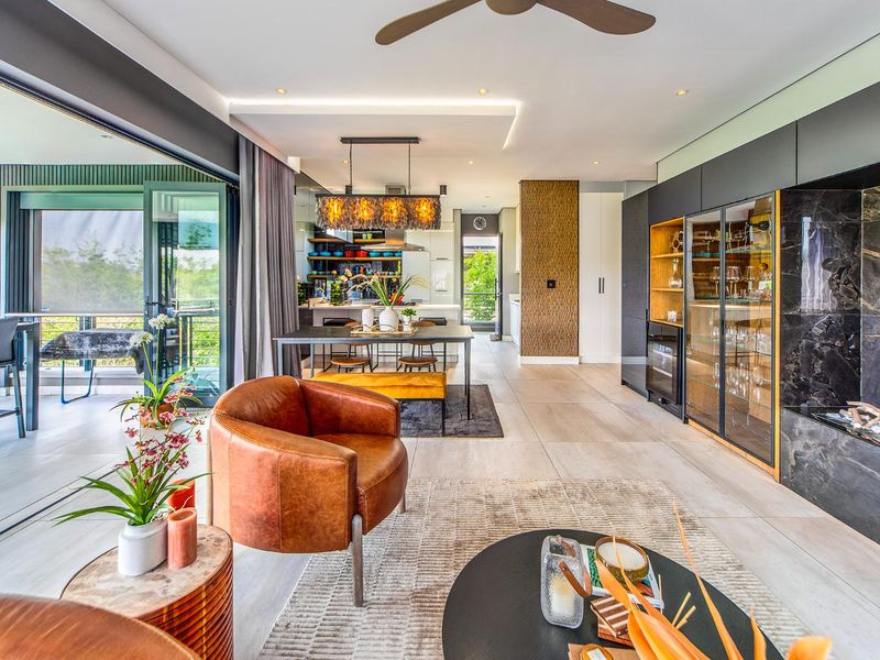 Spacious open-plan living and dining area featuring modern built-in cabinetry, stone accents, recessed lighting, and seamless access to an outdoor balcony through sliding glass doors.