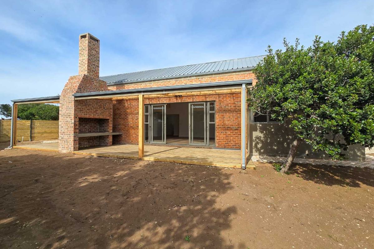 Rear view of the townhouse featuring a brick facade, a covered wooden deck, and a built-in outdoor brick fireplace.