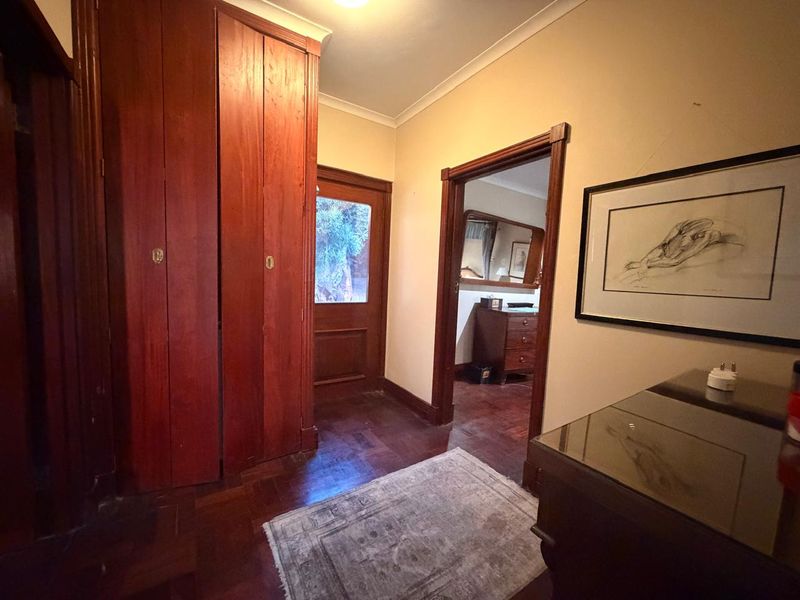 Entrance hall featuring classic timber parquet flooring, built-in wooden cabinetry, and traditional timber door frames leading into the home.