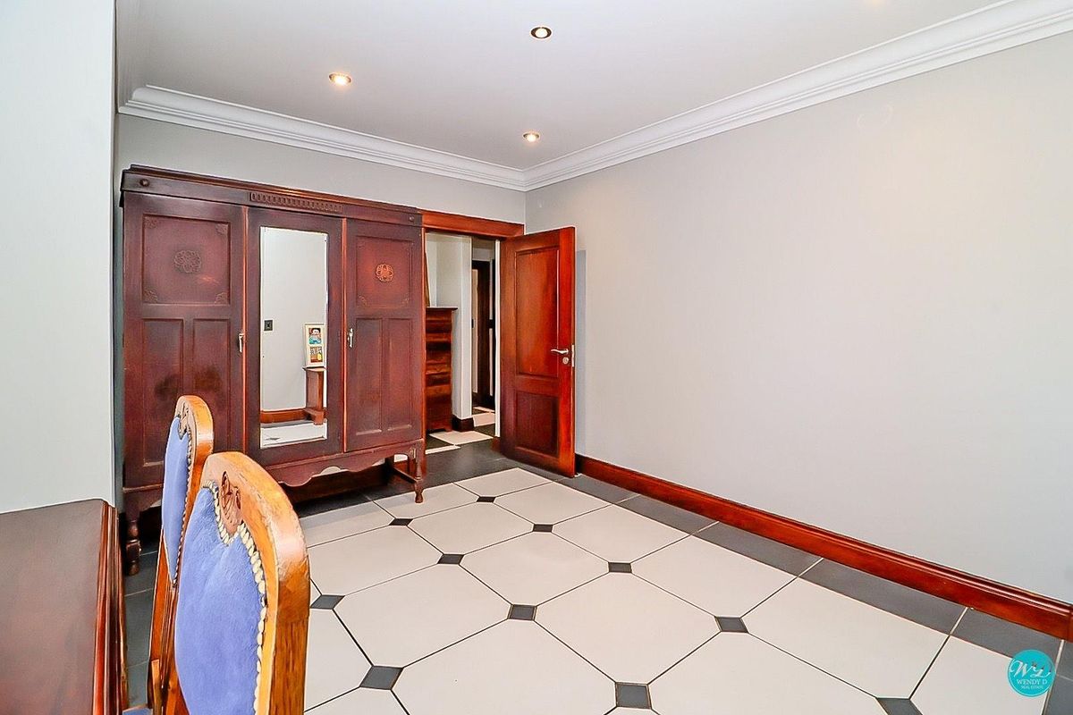 A bedroom featuring tiled flooring with decorative inserts, crown molding, recessed lighting, and solid wooden door finishes.