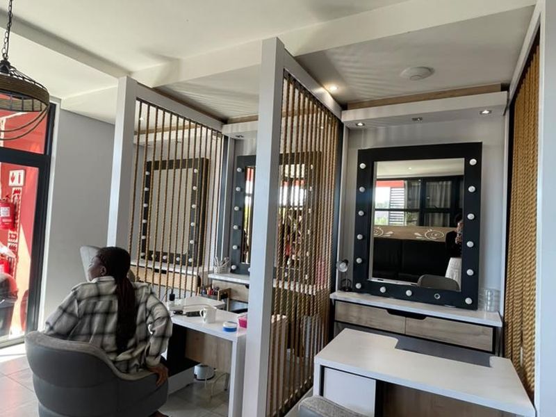 Modern salon or office space featuring individual vanity stations with illuminated mirrors, rope room dividers, and ceiling-mounted air conditioning.