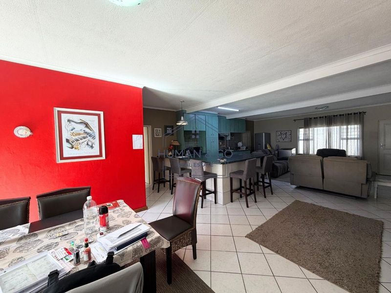 Spacious open-plan living and dining area featuring a central kitchen island with breakfast bar seating and tiled flooring throughout.