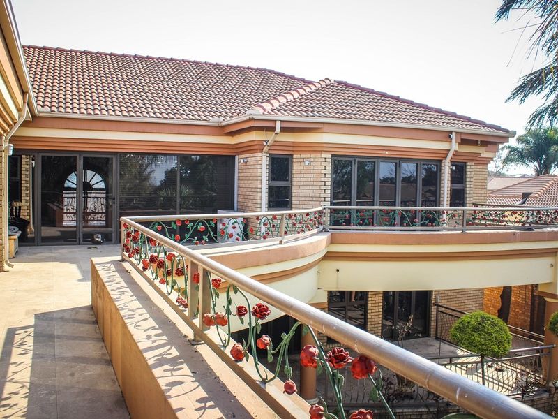 Spacious upper-level balcony featuring decorative metal railings, tiled flooring, and large aluminium sliding doors providing access to the home's interior.