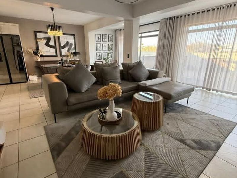 Spacious open-plan living and dining area featuring tiled flooring, modern pendant lighting, and large sliding glass doors that provide ample natural light.