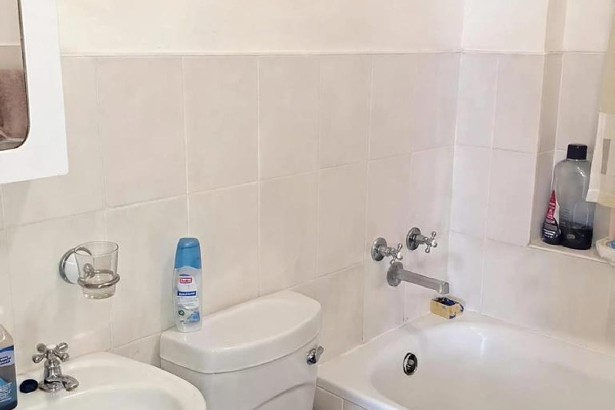 A functional bathroom featuring a pedestal sink, standard toilet, and a bathtub with wall-mounted fixtures and tiled wall surrounds.