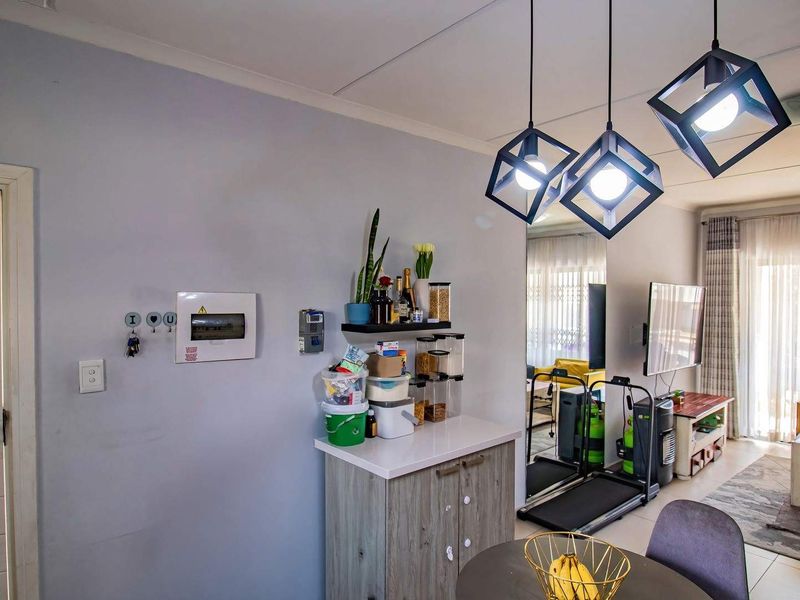 Open-plan living area featuring modern geometric pendant lighting, neutral wall finishes, and access to an outdoor patio through a secure sliding door.