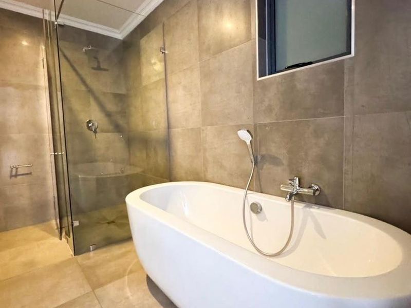 Modern bathroom featuring a sleek freestanding bathtub, a separate glass-enclosed shower, and contemporary large-format wall and floor tiling.