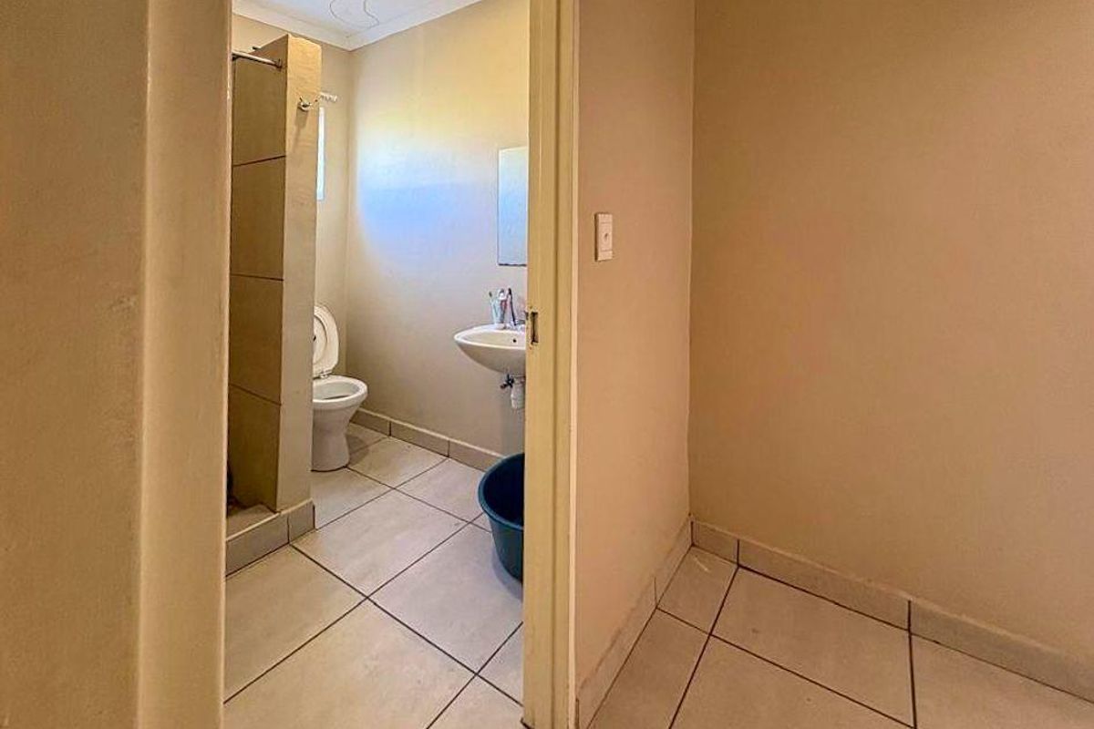 A functional bathroom featuring a pedestal sink, toilet, and a tiled shower enclosure with a partition wall.
