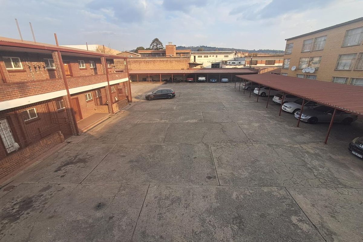 An elevated view of the apartment complex courtyard featuring paved parking areas and covered carports.