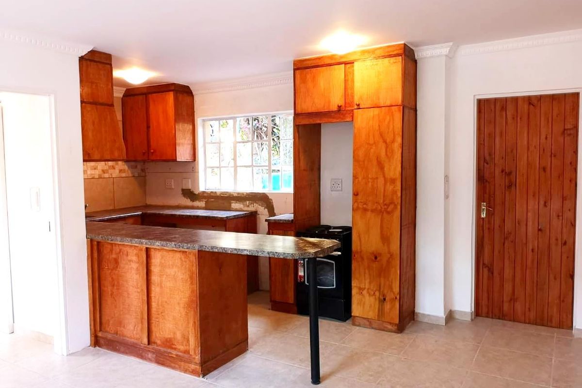 A functional kitchen featuring wooden cabinetry, a breakfast bar, tiled flooring, and a built-in oven, with some areas requiring minor finishing touches.