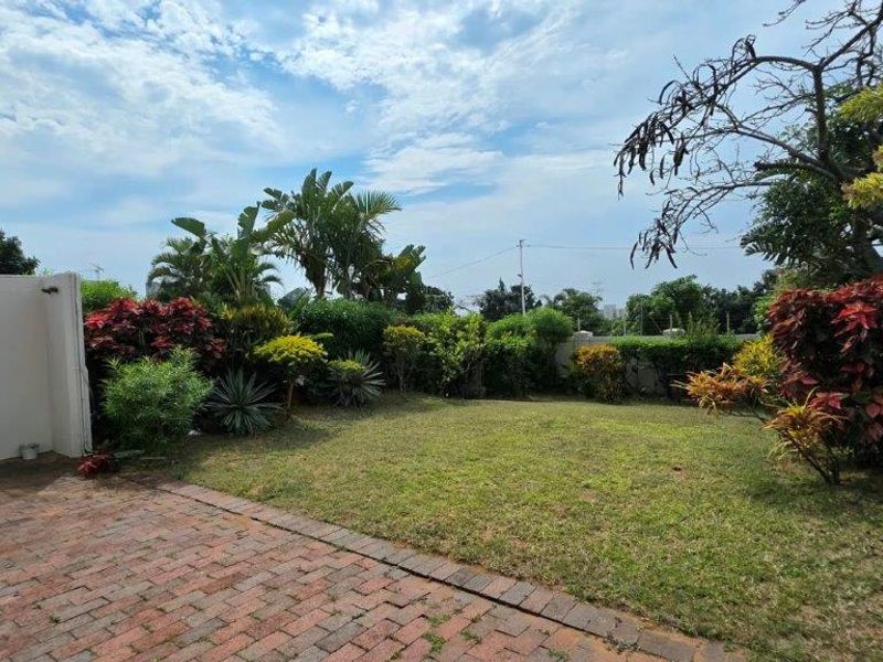 A private rear garden featuring a brick-paved patio area and established landscaped greenery, providing a peaceful outdoor space for the townhouse.