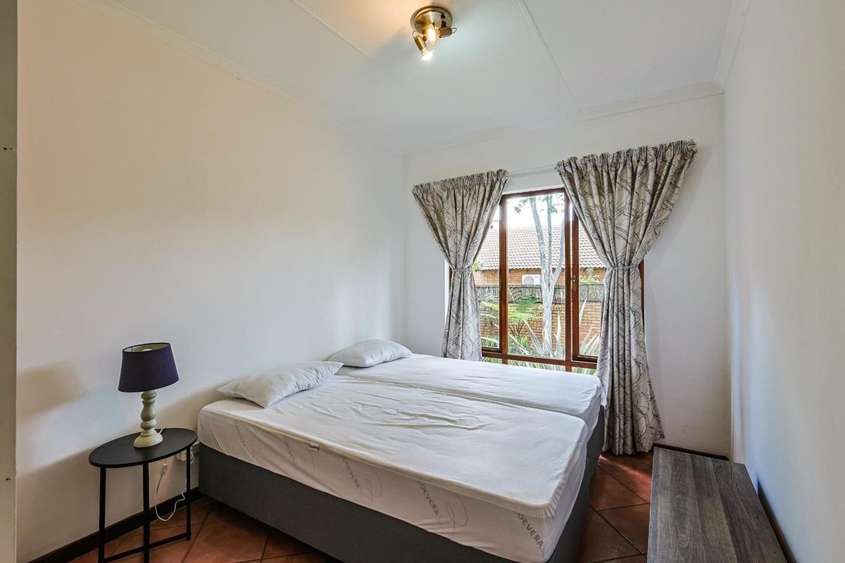 A standard bedroom featuring tiled flooring, a window with curtain tracks, and a central ceiling light fixture.