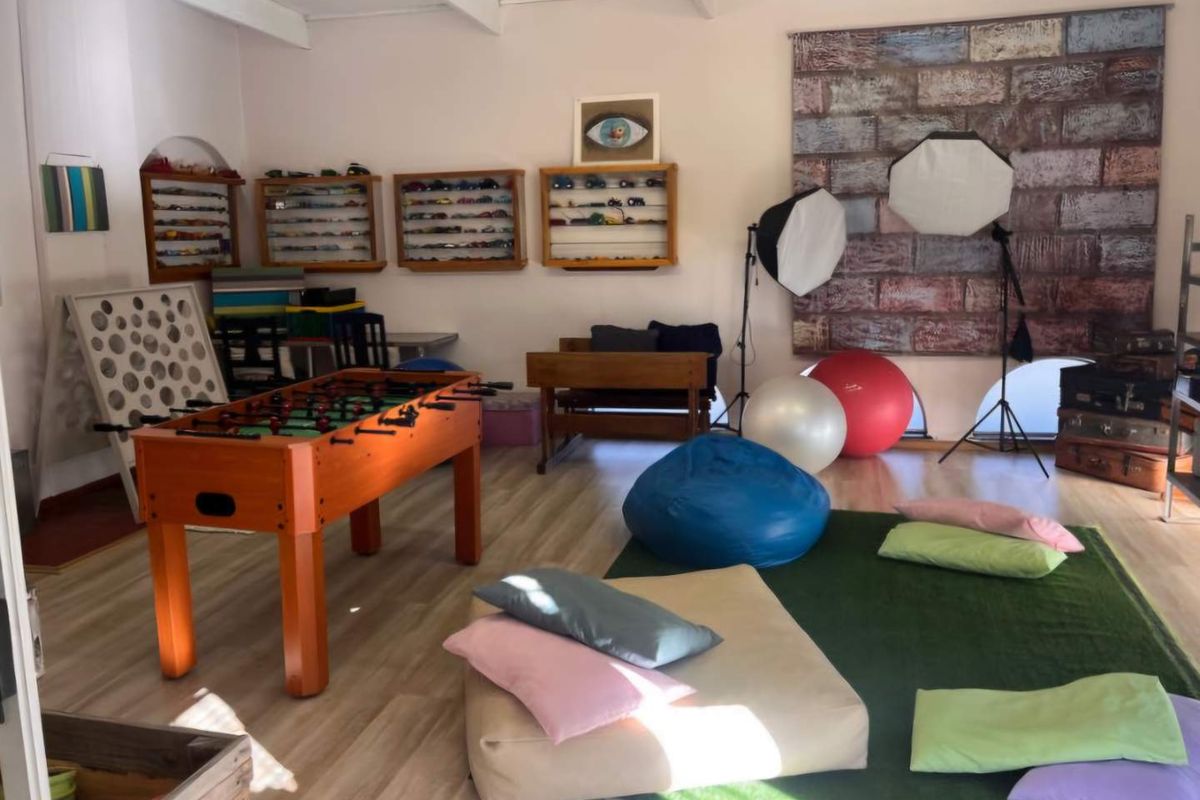 A versatile multi-purpose room featuring light wood-look flooring, exposed ceiling beams, and built-in wall-mounted display shelving.